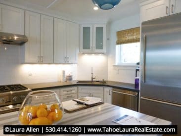 View of new beach style kitchen with free standing island, white cabinets stainless steel appliances and gray marble solid surface counter tops.